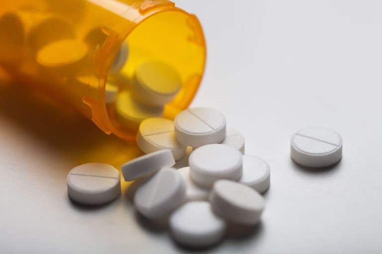Amber prescription bottle with spilled white tablets